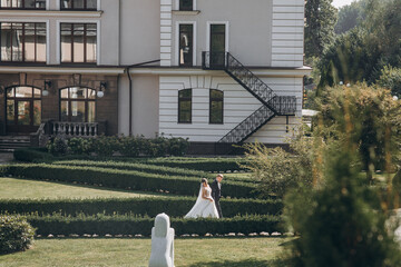 couple in love at their wedding walking in the park in the front of large gray architecture