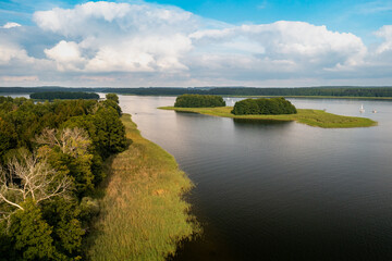 Fototapeta premium Aerial view of green islands and clouds at summer sunny day. Masurian Lake District in Poland. 