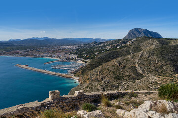 Fototapeta na wymiar View of the blue mediterranean sea and a port of a coastal city and a beautiful mountain landscape in Spain