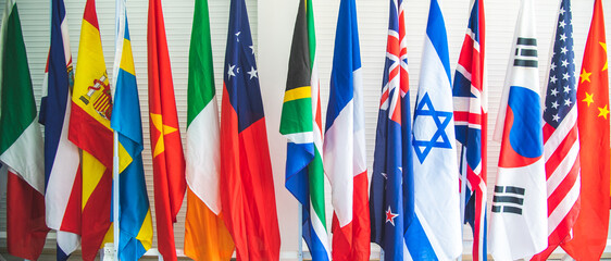 Closeup of a collection of various flags of different countries standing tall together in a row on...
