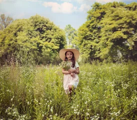 Gordijnen Portrait of cute kid girl with bloom flowers. Nature outdoor. Child in nature concept. © konradbak