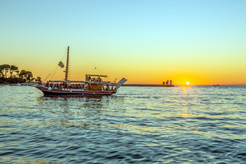 Fototapeta premium Image of a sunset from the harbor of the Croatian coastal town of Porec with a passing tourist boat