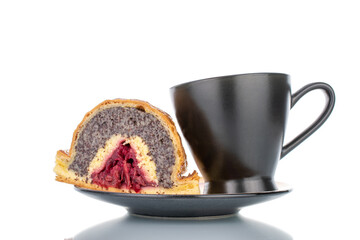 One piece of cherry poppy strudel on a black ceramic saucer with a black cup, close-up, isolated on white.