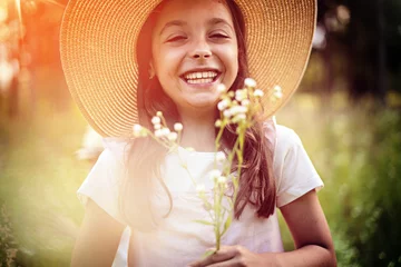 Tuinposter Portrait of cute kid girl with bloom flowers. Nature outdoor. Child in nature concept. © konradbak