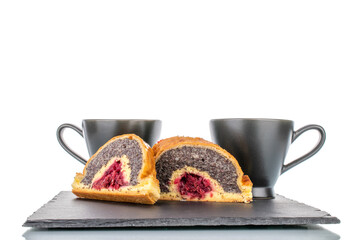 Two pieces of cherry poppy strudel on a slate stone with two black cups, close-up, isolated on white.
