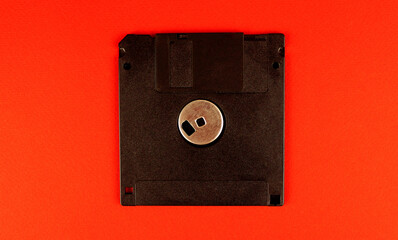 Old black floppy disk on red background