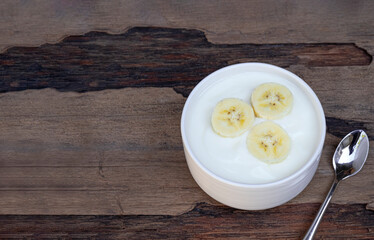 Fruit yogurt has banana and honey greek white clean In bowl on a wooden background from top view.

