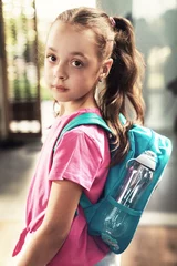 Foto op Canvas Happy schoolgirl with backpack smiling and looking at camera © konradbak