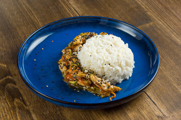 Teriyaki chicken dish with rice and vegetables on wooden background