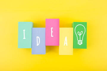 Creativity and idea concept. Single word idea and light bulb drawn on multicolored rectangles on yellow background