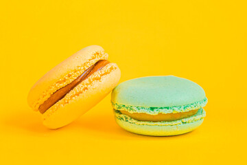 Sweet almond colorful unicorn blue yellow macaron or macaroon dessert cake isolated on trendy yellow modern fashion background. French sweet cookie. Minimal food bakery concept Copy space