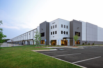 Modern gray industrial warehouse distribution building and parking lot - Powered by Adobe