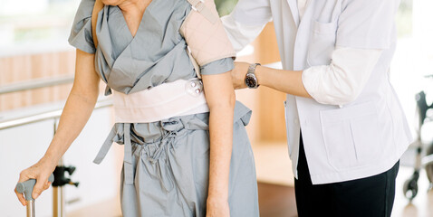 Physiotherapist helping senior woman with walker at remedial gymnastics