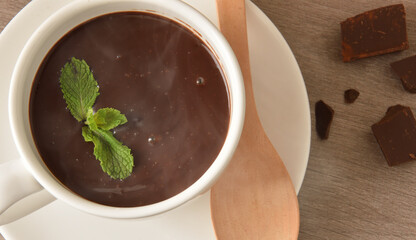 Liquid chocolate detail in white cup on plate and chunks