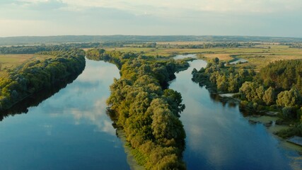 Aerial view above a beautiful landscape with a  river while sunset. Aerial view from drone flies over a beautiful summer landscape.