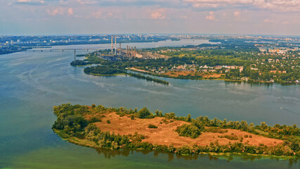 Photo from a drone of a beautiful summer landscape over the river. Beautiful summer landscape with a wide river and green coastline. Aerial photography of the suburban landscape.