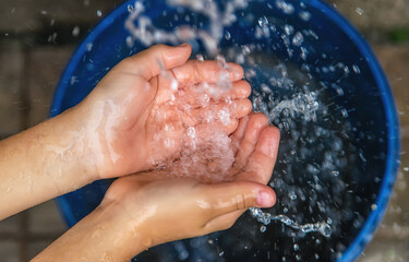 The water flows into the hands of the child. Selective focus.