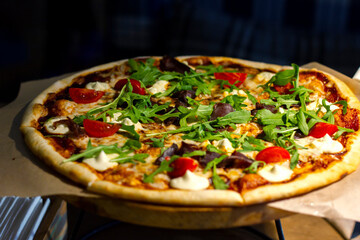 fresh pizza with pieces of meat, tomatoes and herbs with mozzarella cheese close-up