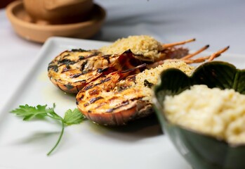 lobster cut into two parts, decorated with green vegetables on the plate
