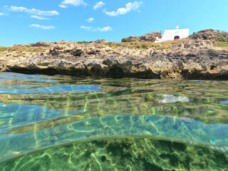 Underwater split photo of iconic small chapel of Agios Ermolaos built in a small islet, Skyros island, Sporades, Greece