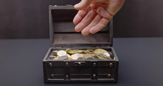 Hand putting coins into treasure chest slow motion footage
