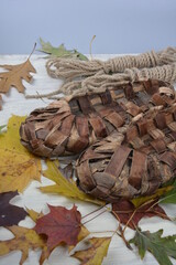 Birchen woven bast shoes hang on a log wall.