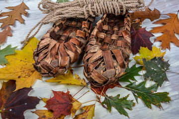 Birchen woven bast shoes hang on a log wall.