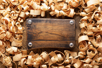 Wood shaving and name plate on table background. Wooden shavings at old plank board texture