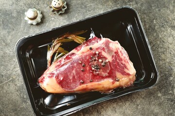 Raw fresh New York steak mixed with peppers and rosemary.