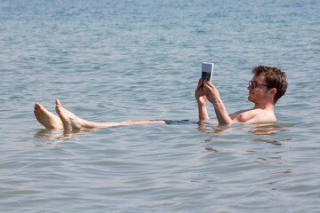 Junger Mann liest Buch im Toten Meer