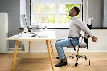 Employee Stretching At Office Desk