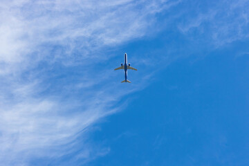 Big beautiful blue and white plane flying in the cloudy blue sky