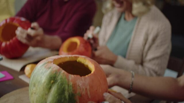 A man and his family draws on the pumpkins with a marker. Close up, slow motion
