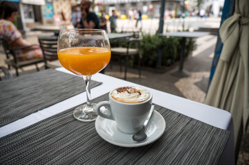 Cup of coffee with freshly squeezed orange juice on a table.