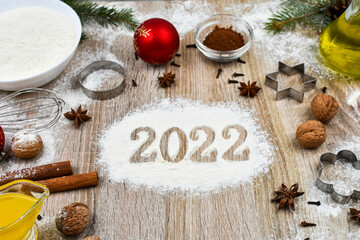Products for baking homemade Christmas cookies on a wooden background with the inscription 2022. The concept of the holiday, celebration and cooking.