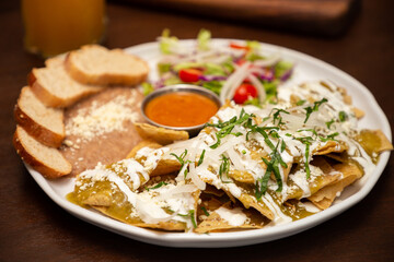 Chilaquiles verdes con frijoles refritos y pan.