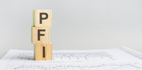 PFI - Private Finance Initiative acronym, wooden blocks, business concept, gray background