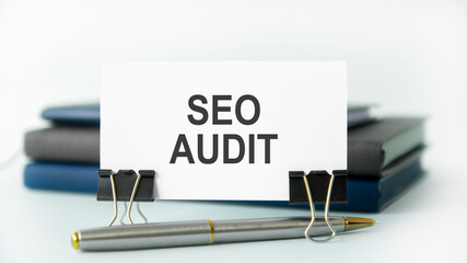 a white notebook with the text Seo Audit lies on a white paper card