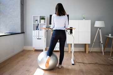 Woman Using Adjustable Height Standing Desk In Office