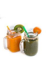 Healthy vegetable smoothies in green and yellow jars on a white background