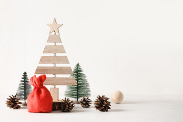 Creative wooden Eco Christmas tree, Santa Claus bag and pine cones on white background. DIY....