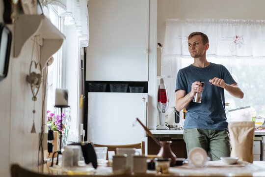Thoughtful man with pepper mill in kitchen