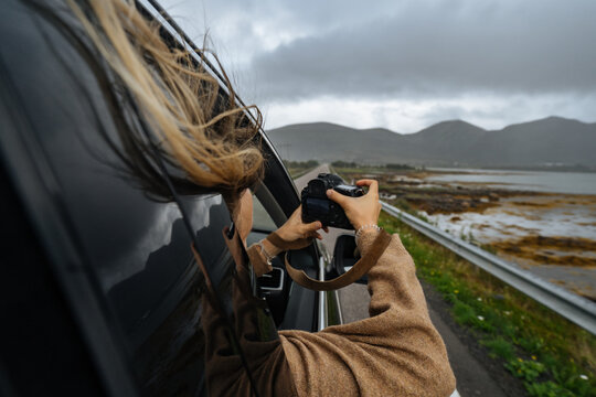 Woman in driving car photographing nature