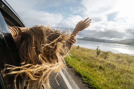 Anonymous woman leaning out from car window in nature