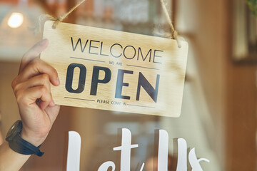 Faceless owner holding signboard open in cafe 