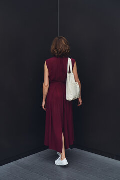 Stylish woman in corner of empty room with dark walls