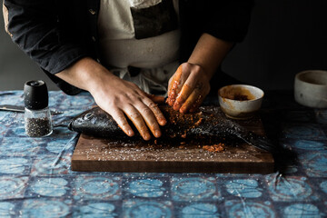 male chef seasoning whole fish 