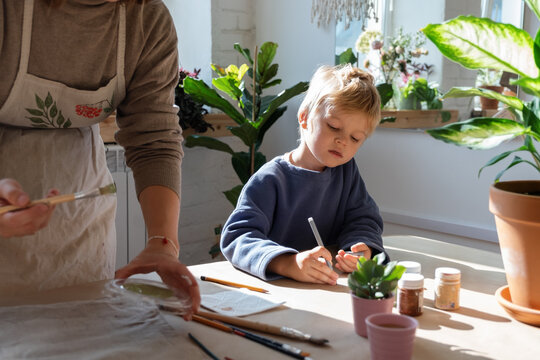Boy sketching near painting woman