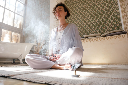 Woman inhaling incense smoke during meditation