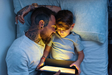 Father sleeping near son with tablet